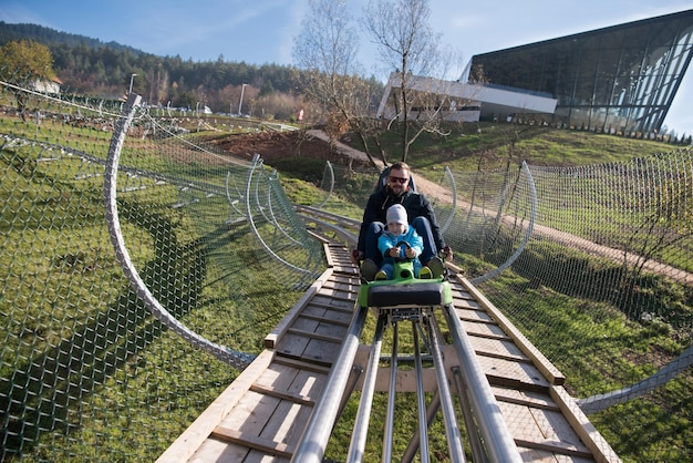 Foto padre e figlio si divertono a guidare sulle montagne russe alpine