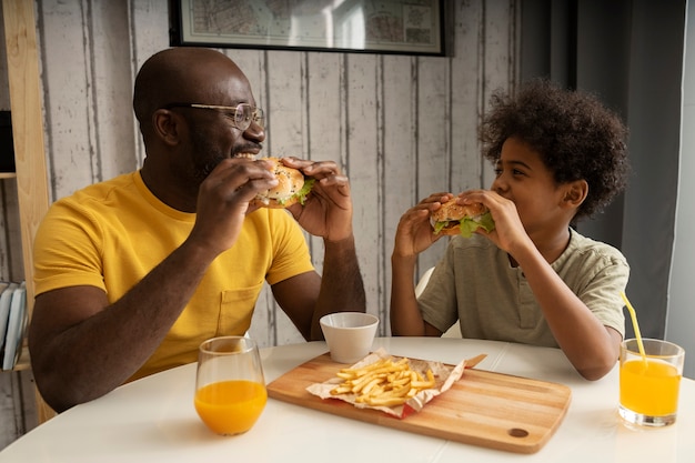 Foto padre e figlio mangiano patatine fritte e hamburger insieme