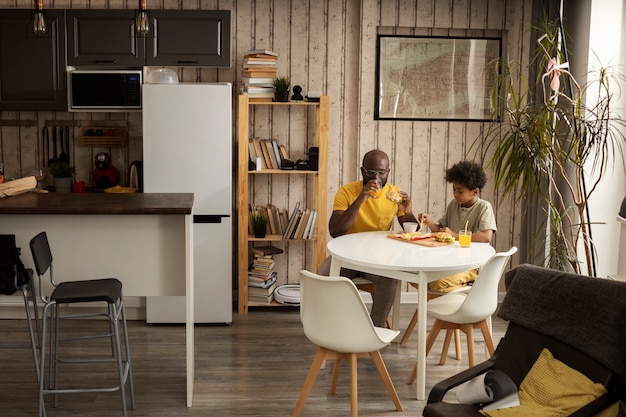 Photo father and son having french fries and burgers together