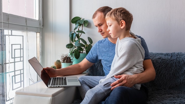 Padre e figlio che hanno videochiamata con i nonni sul laptop soggiorno a casa, concetto di comunicazione a distanza