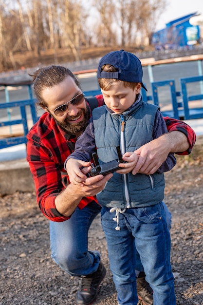 Father and son holding remote control joystick and piloting copter