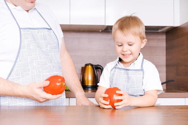 父と息子の家でキッチンに立って、赤を持って笑顔で一緒に