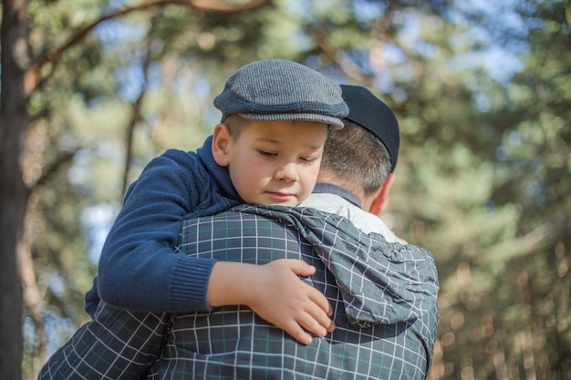 Father and son hugging in autumn park, shallow depth of field. Active family vacation