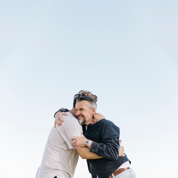 Father and son hugging on sky background