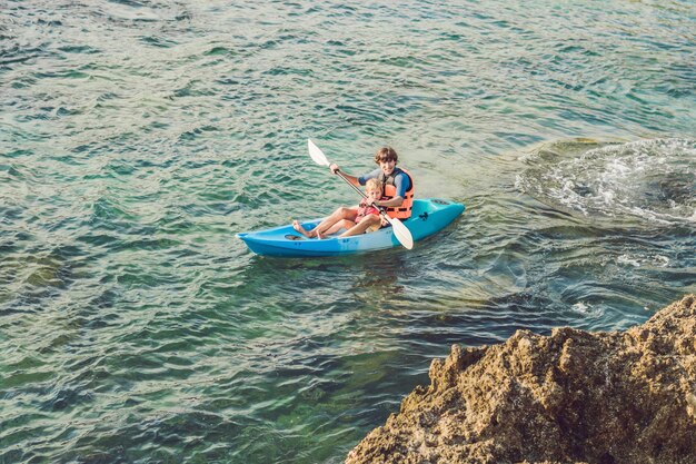 Father and son kayaking at tropical ocean.