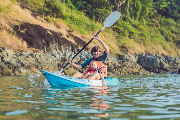 Father and son kayaking at tropical ocean.