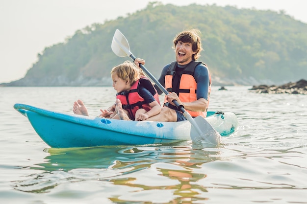 Father and son kayaking at tropical ocean.