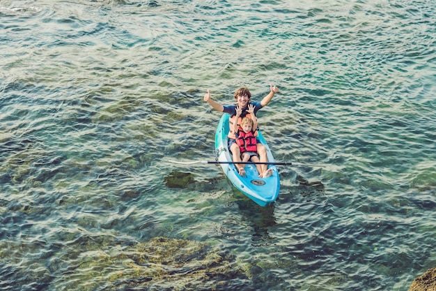 Father and son kayaking at tropical ocean.