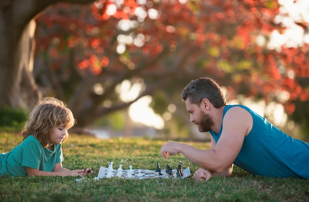 Father and son kid playing chess spending time together outdoor