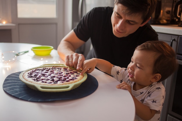 Father and son in the kitchen. kid wants a delicious hot cake.