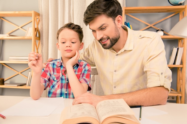 Father and son laughing while reading book at home