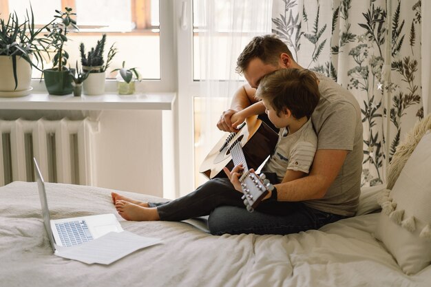 Padre e figlio imparano a suonare la chitarra acustica in una lezione online