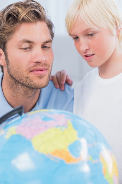 Father and son looking at globe together