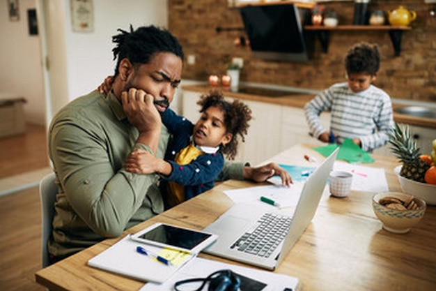 a father and son looking at a laptop with a child on the table