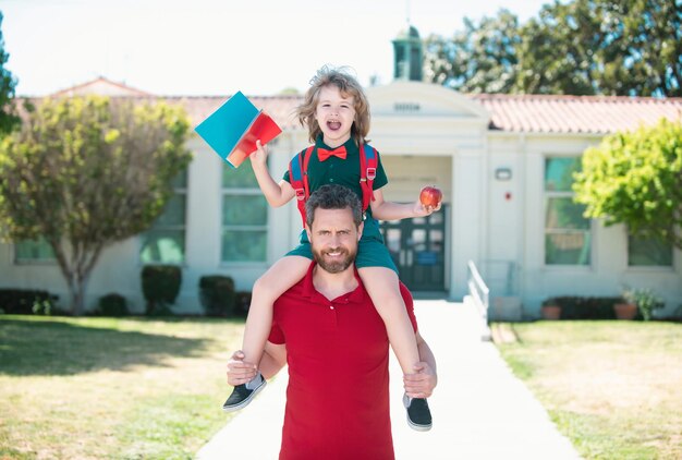 Father and son piggyback ride trough school park