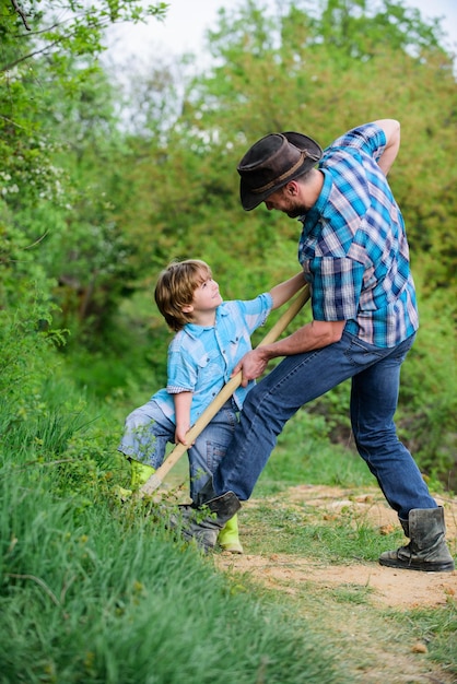 Father and son planting family tree rich natural soil Eco farm Ranch small boy child help father in farming new life soils and fertilizers happy earth day Dig grounf with shovel Little plant