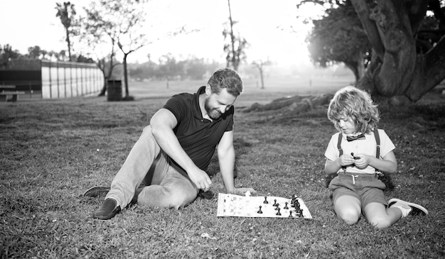 Foto padre e figlio giocano a scacchi sull'erba nell'infanzia del parco estivo