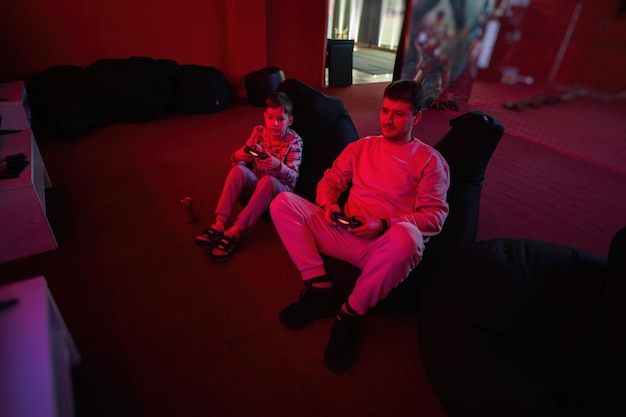 Father and son play gamepad video game console in red gaming room Dad and kid gamers