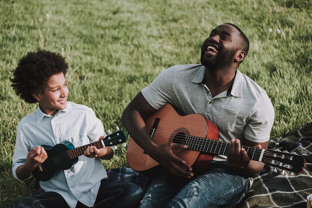 Father and Son Play on Guitars on Picnic