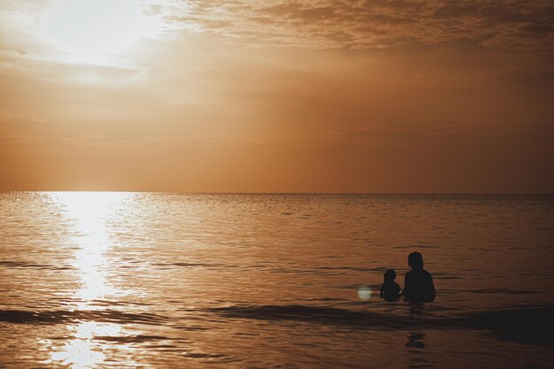 Father and son playing in the beach at the sunset time. People having fun on the field.