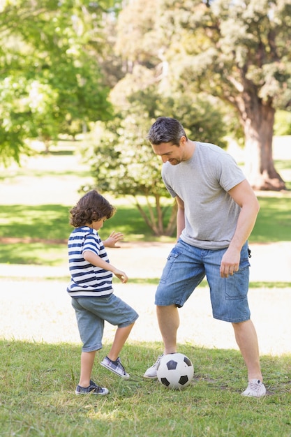 公園でサッカーをする父と息子