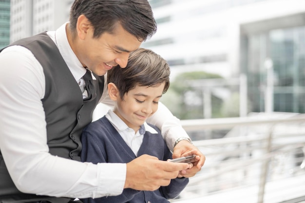 Father and son playing game smart phone together on business district urban Dad and Son happy family concept