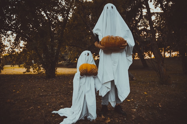 父と息子が庭で白いシーツで幽霊を再生