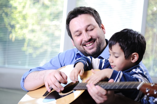 Father and son playing guitar at home