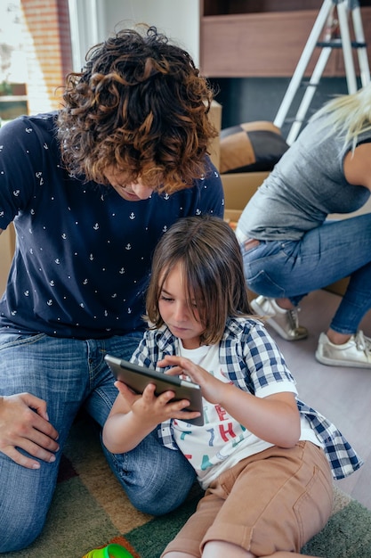 母親が段ボールを開梱している間、父と息子はタブレットを再生します