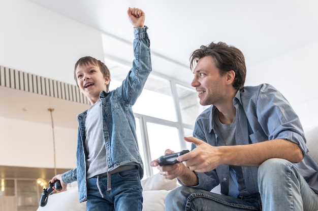 Photo father and son playing video game at home