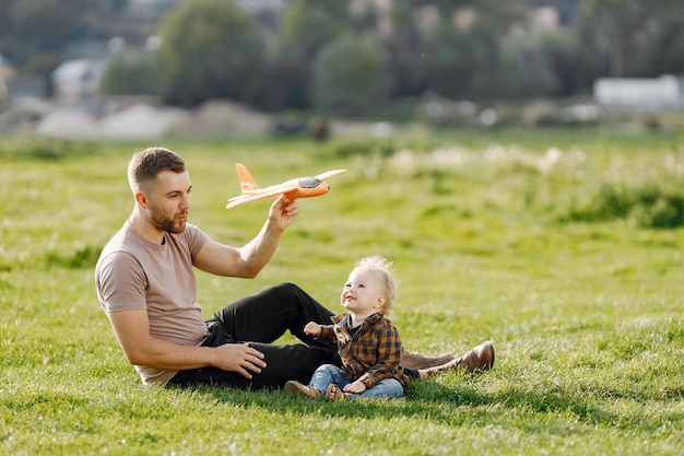 Padre e figlio che giocano con un aereo giocattolo e si divertono nel parco estivo all'aperto bambino riccio con jeans e camicia a quadri