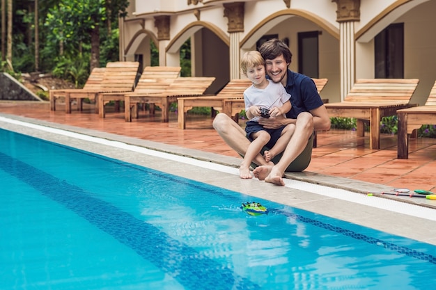 Father and son playing with a remote controlled boat in the pool