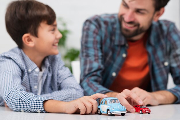 Father and son playing with toy cars and looking at each other