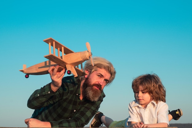 Отец и сын, играя с игрушечным самолетом на открытом воздухе. Семейный праздник, детство отцовства. День отца.