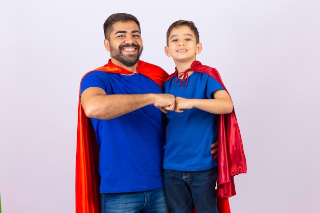 Father and son in red and blue superhero costumes Father and son playing on white background in hero outfit Father's Day
