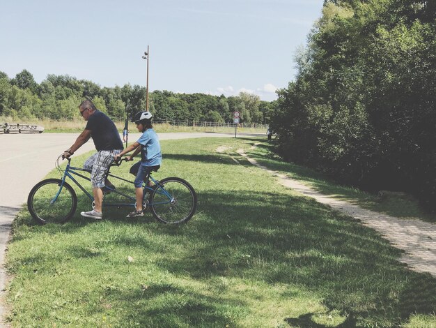 Photo father and son riding bicycle on field