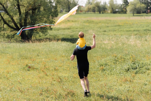 Father and son run in the field with a kite