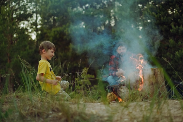 Father and son sitting by fireplace Camping concept Image with selective focus