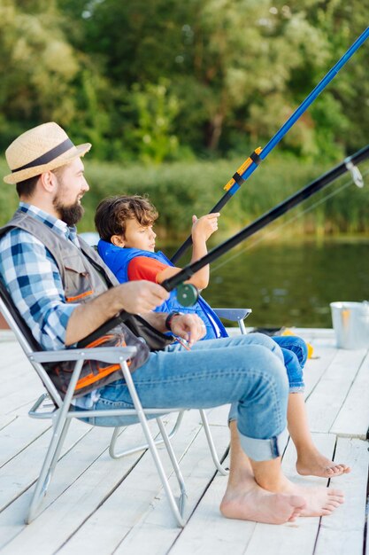 Father and son sitting in chairs while fishing in the\
morning