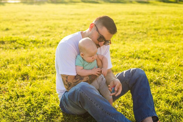 Photo father and son sitting on grass