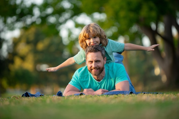 Father and son smiling against summer blurred background at the spring park