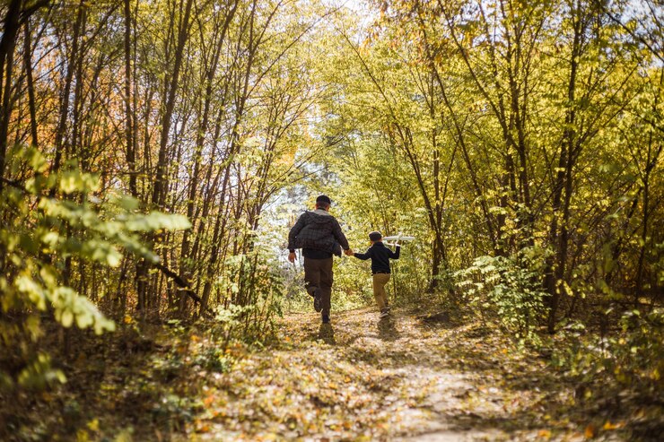 Photo father and son spend time in forest. happy dad and child boy enjoying autumn time on vacation in a sunny park. kids love parents affection and tenderness, lovely family.