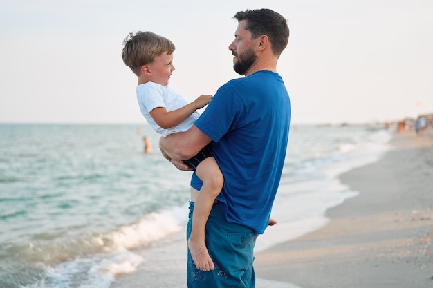 一緒に海の休暇を過ごす父の息子若いお父さんの子小さな男の子がビーチを歩く