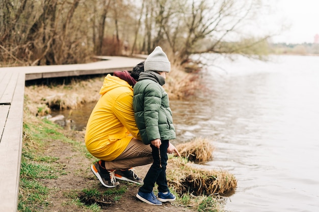 Father and son stand on the shore of the lake and playing with water happy family with child kid boy