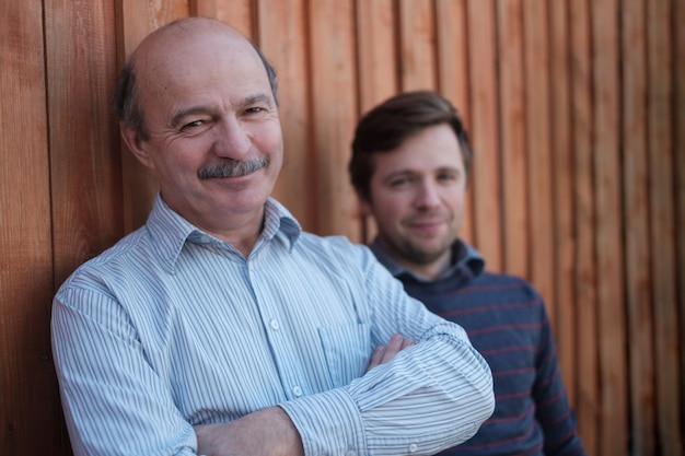 Father and son stand together near wooden background