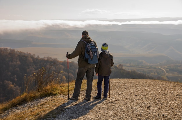 Father and son standing on top of a mountain and looking into the distance