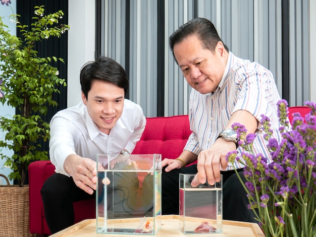 Father and son talking about betta fish in living room.