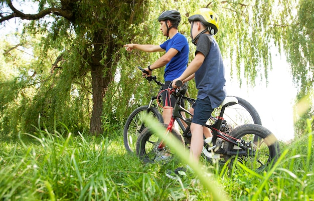 Father and son together are riding bicycles through the pathway