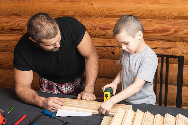 Father and son together make a wooden birdhouse in the workshop