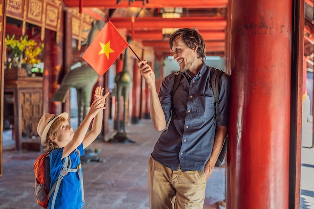 ベトナムの首都ハノイにある文学の寺院 (Temple of Literature in Hanoi in Southeast Asia) に父と息子の観光客が訪れコロナウイルス (COVID-19) による隔離の後ベトナムではコンフューシウスの寺院が再開されました